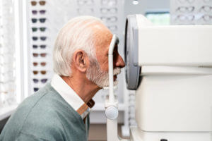A senior man is undergoing an eye health check during a diabetic retinopathy screening.