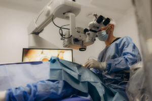 A surgeon looks through a microscope in the operating room during eye surgery or a diagnosis for laser cataract surgery and diopter correction.