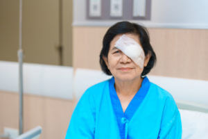An elderly woman wearing an eye protection shield after custom LASIK eye surgery.