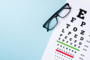 Eye test chart and glasses on blue background.