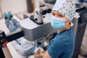 Happy laser eye surgeon during laser eye surgery looking at camera .